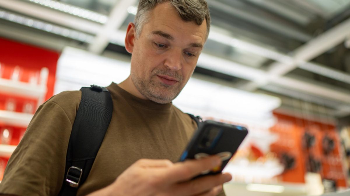 A man checking his phone while standing in a store.