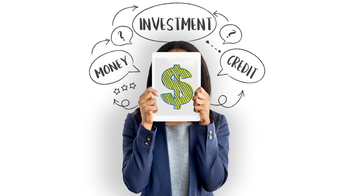 A woman hiding her face behind a tablet showing a dollar sign, surrounded by speech bubbles reading money, investment and credit.