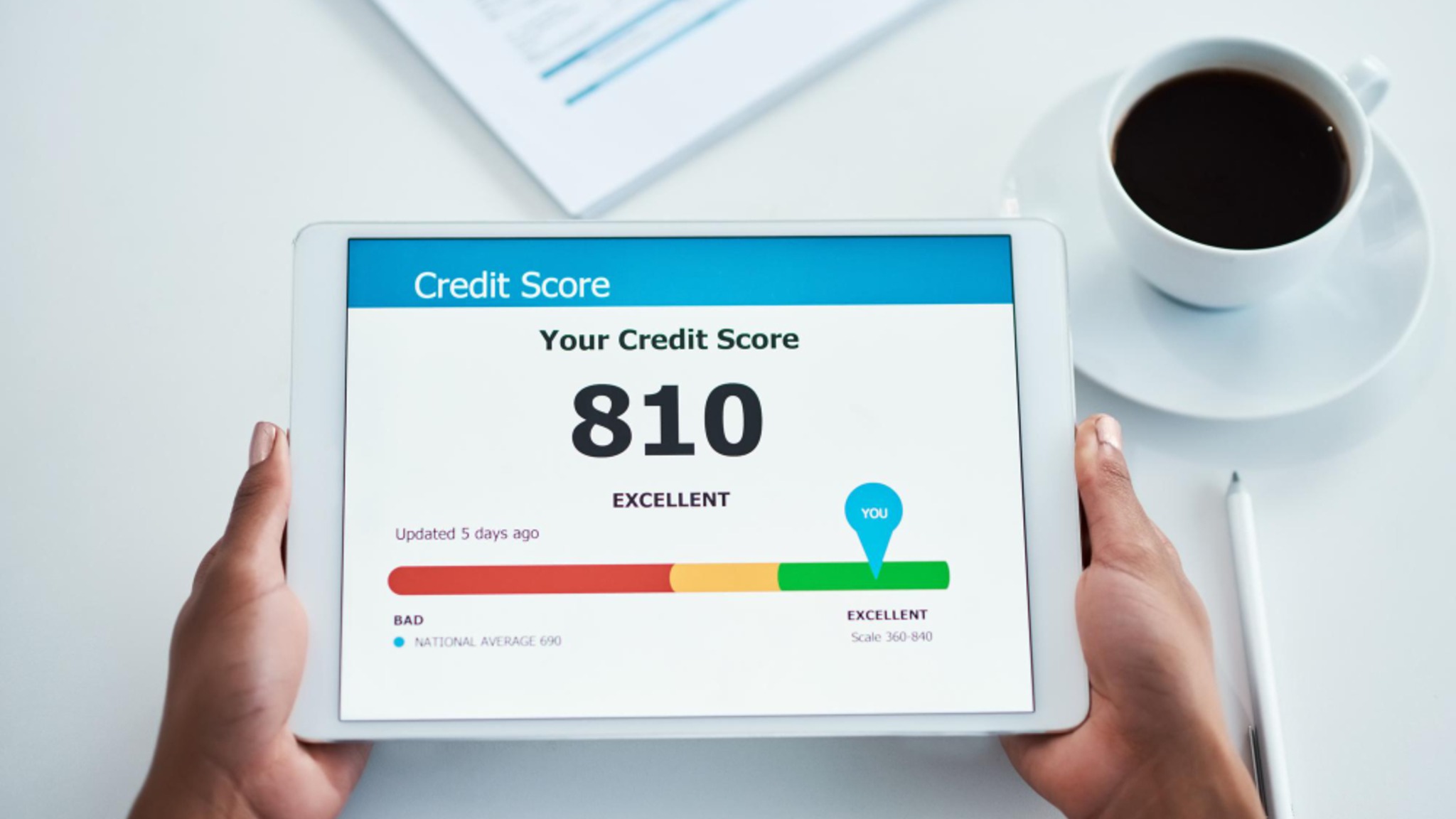 A tablet showing a credit score dashboard with a score of 810 on a good-to-excellent scale.
