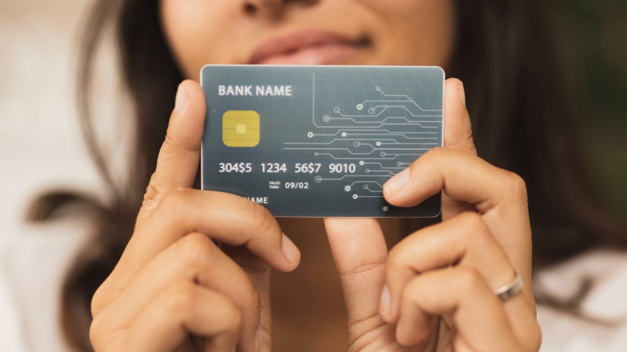 A young woman holding up a credit card with both hands.